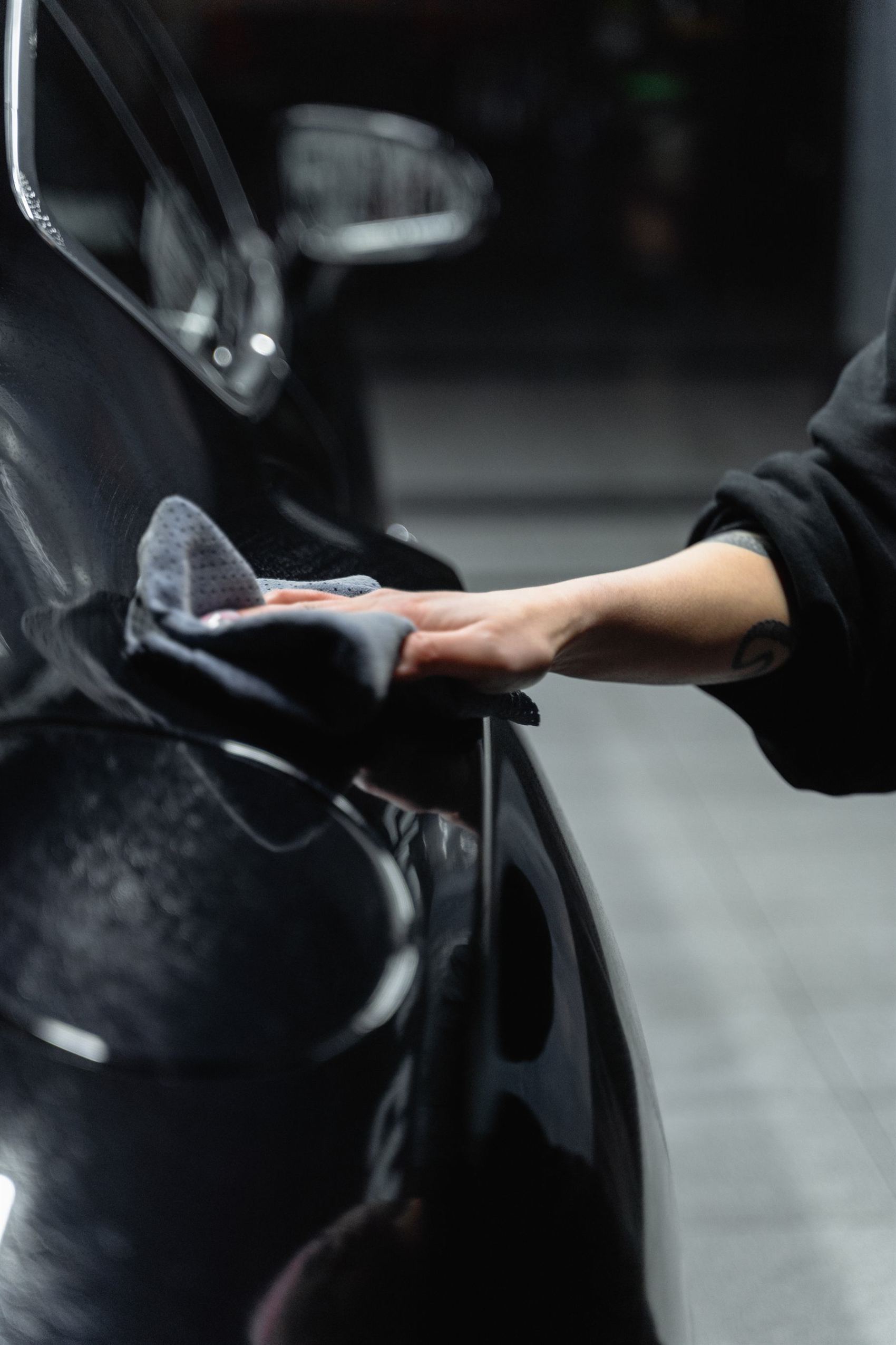 Hand finishing a glossy black car with a microfiber towel